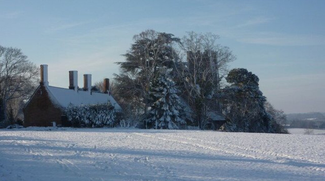 View southwest across a snowy field at Elmswell, Suffolk. On the left are the almshouses, built in 1614. Centre right behind the trees is the parish church of St John the Divine
