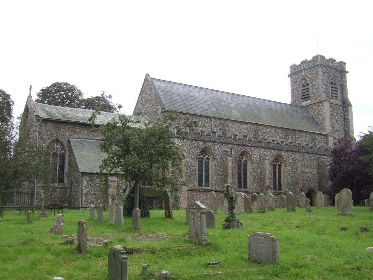 A historic church with a tower and multiple tombs in the foreground.