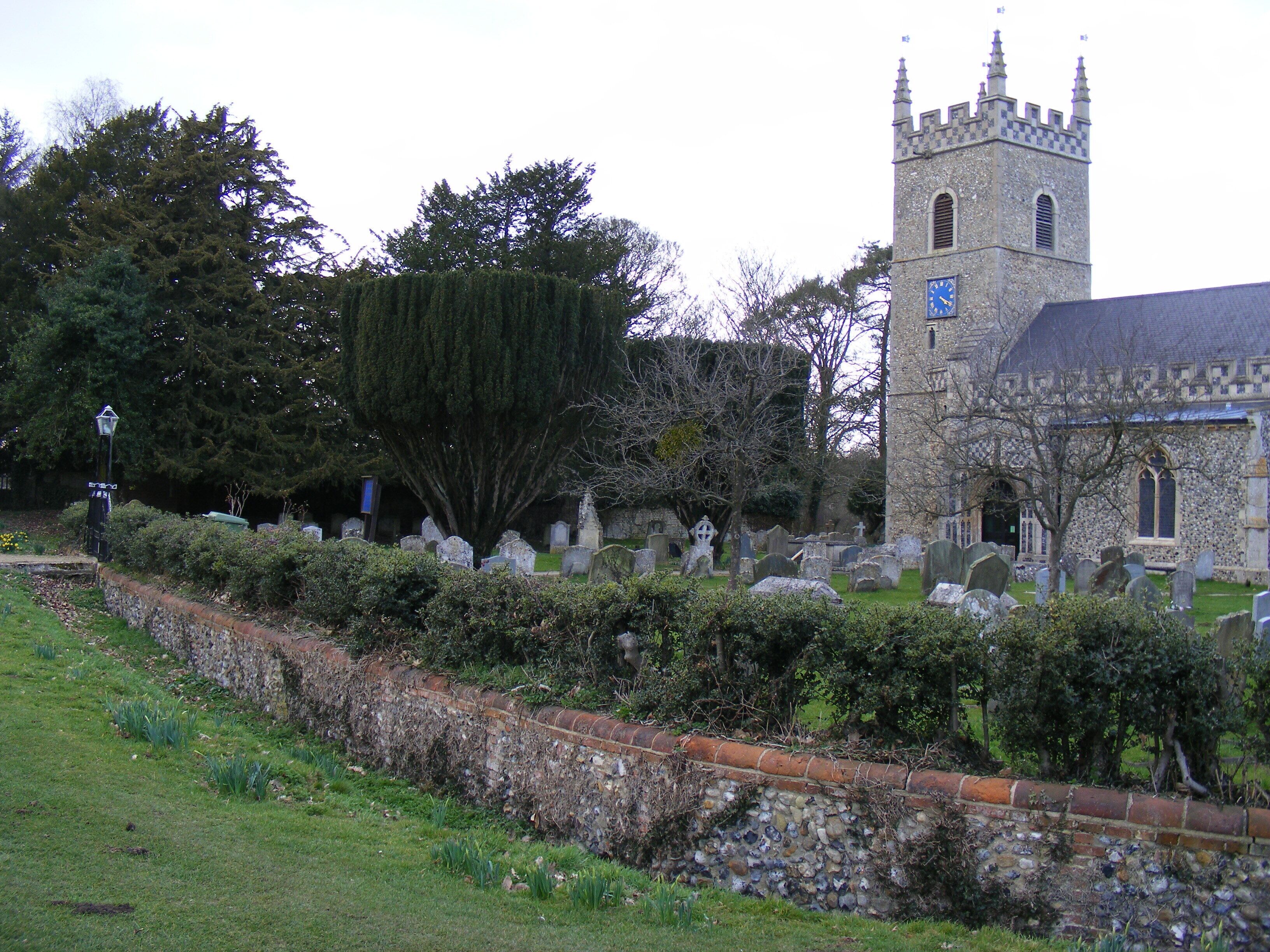 A church with a tall tower and a cemetery with headstones.
