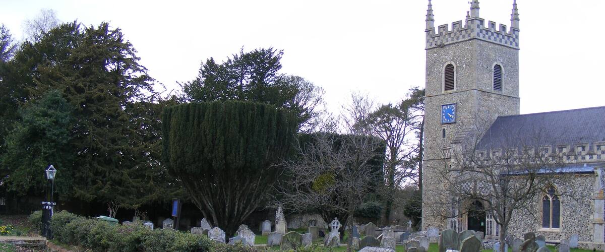 A church with a tall tower and a cemetery with headstones.