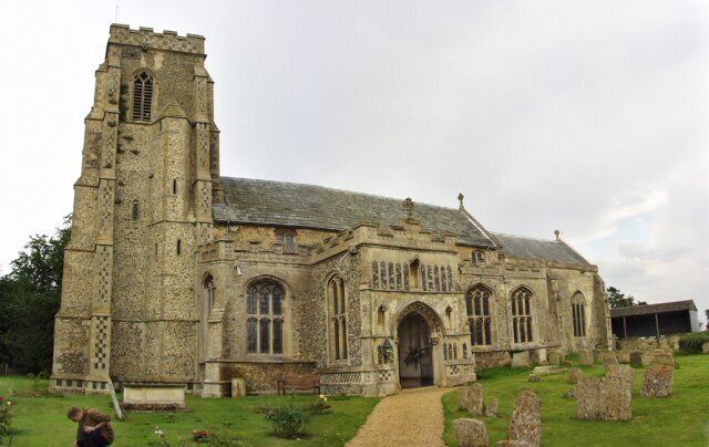 A historic stone church with a tall bell tower and arched windows.