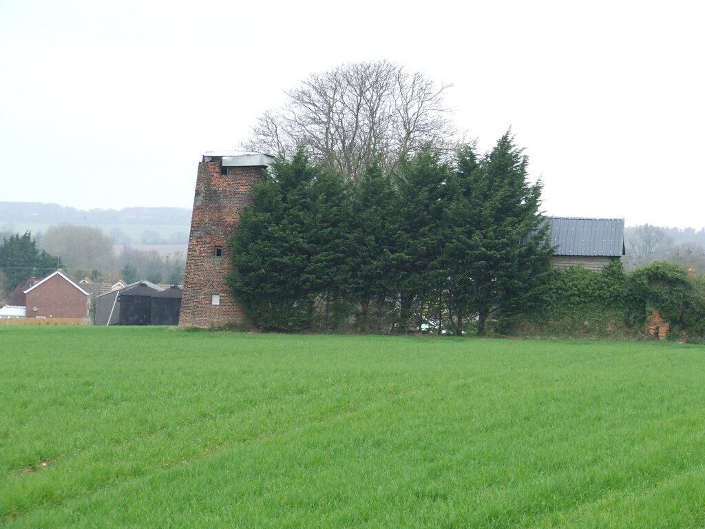 A brick tower, a large tree, and a grassy field.