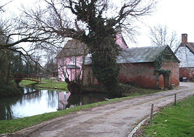 A canal with a pink house and a brick building.