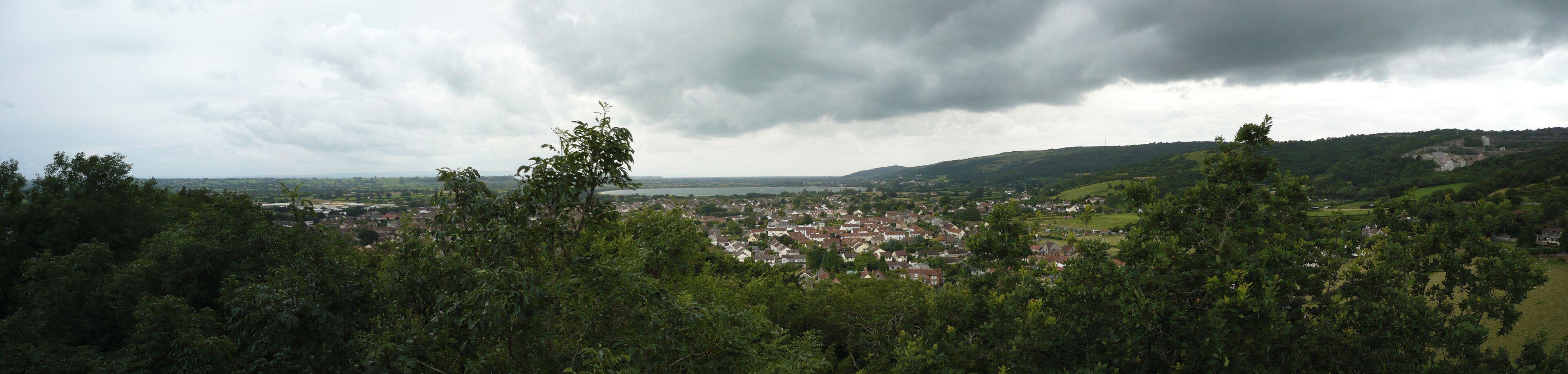 Panoramic view of Cheddar village, Somerset, UK. Cheddar Reservoir seen in the background. Photo taken from Jacob's Ladder on the Mendip Hills.