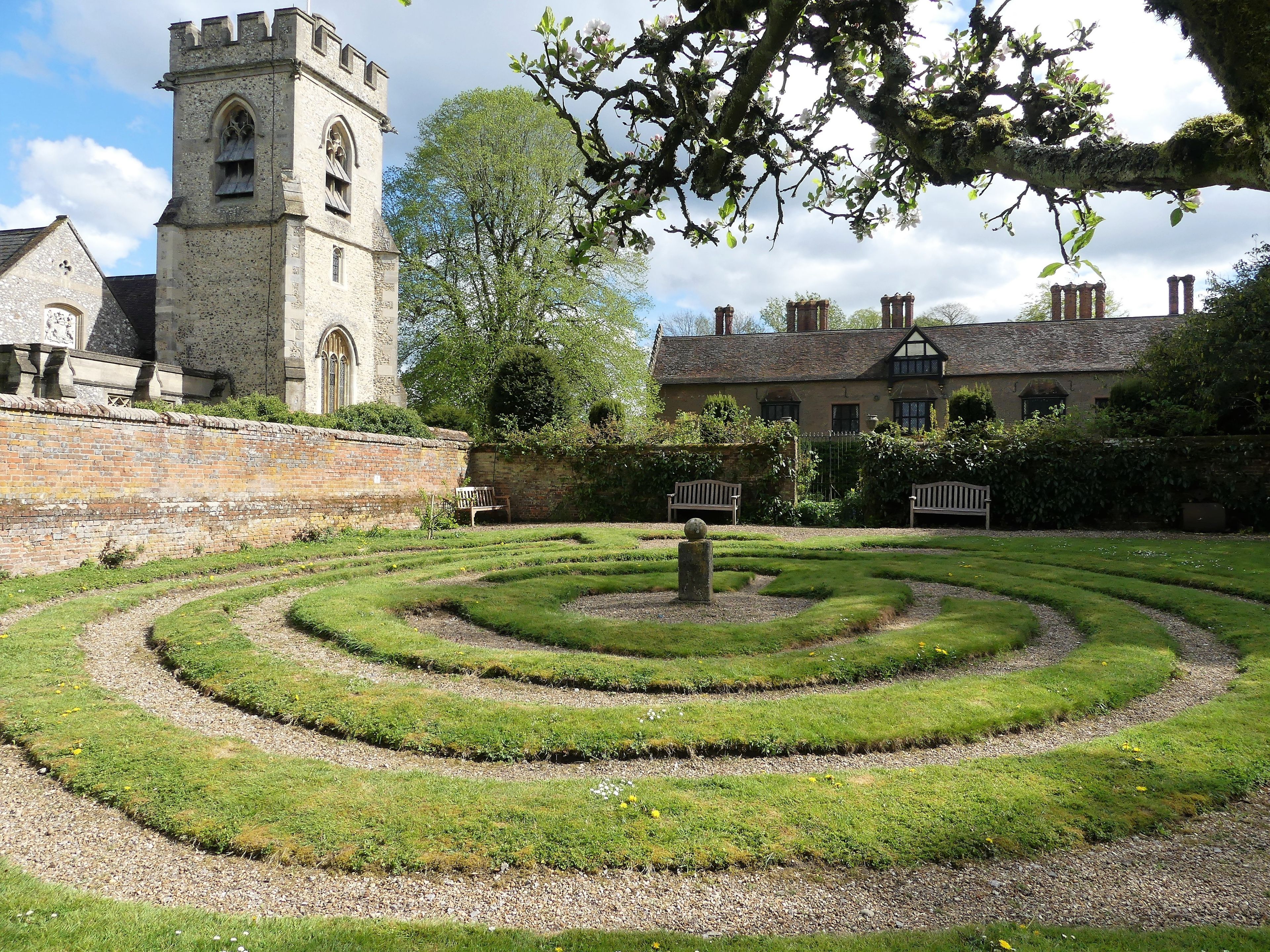 A historic church with a tower, a maze garden, and a stone wall.