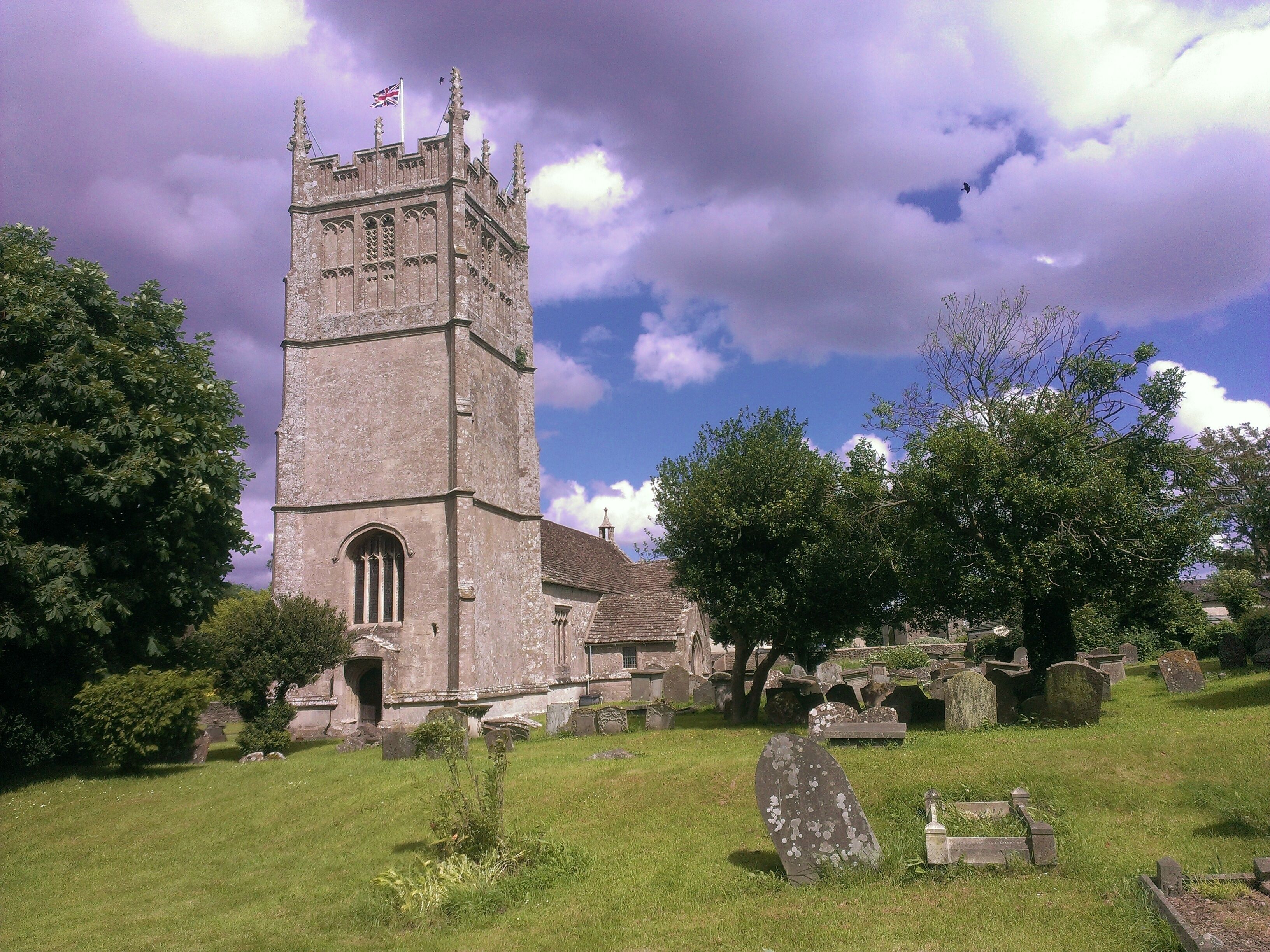 A historic church with a tall tower, surrounded by a cemetery with headstones.