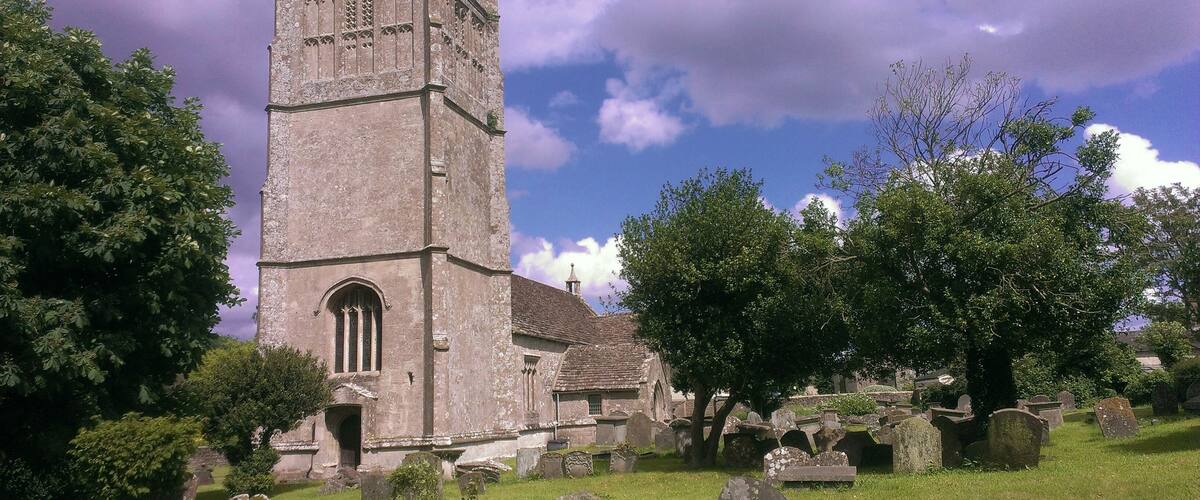 A historic church with a tall tower, surrounded by a cemetery with headstones.