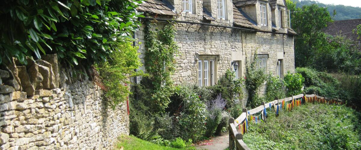 A stone house with a steep roof and multiple chimneys.