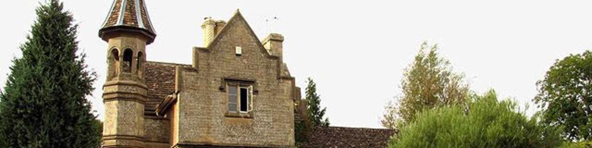 A historic stone building with a tower and a large garden.