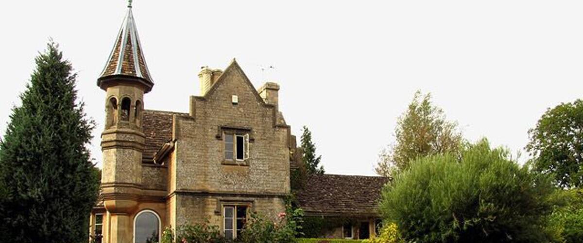 A historic stone building with a tower and a large garden.