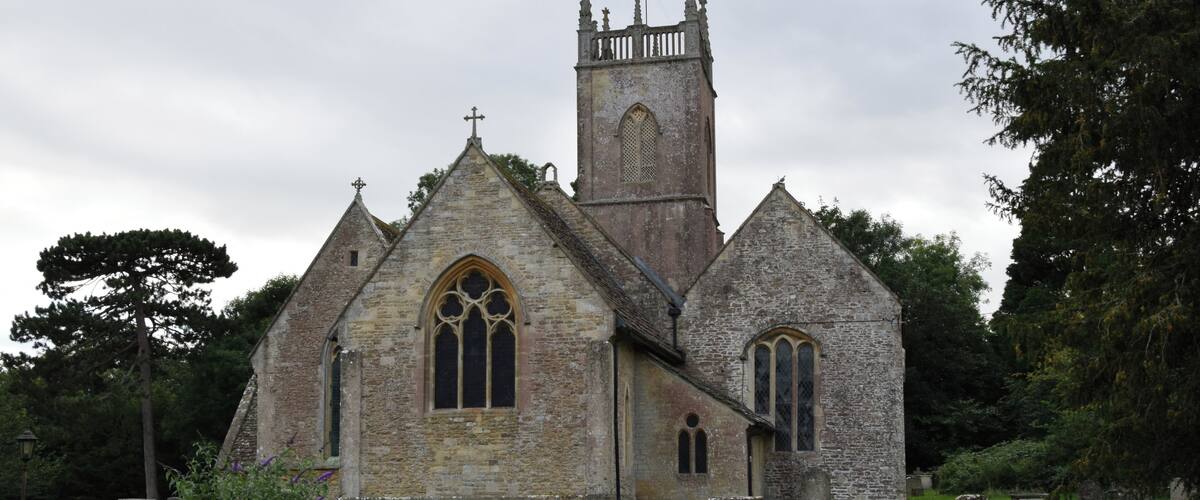 A historic stone church with a tall bell tower and arched windows.