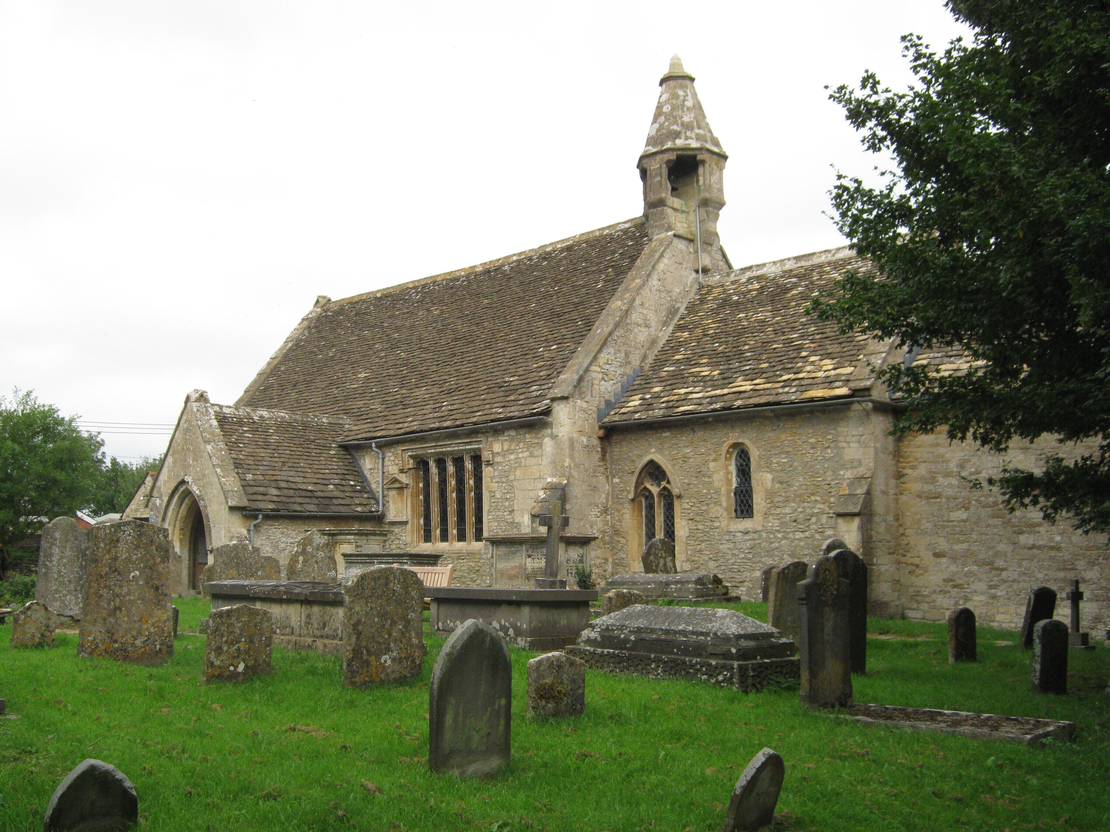 A historic church with a stone facade, a pointed steeple, and a surrounding graveyard with headstones.