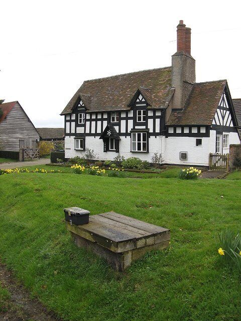 Village green, Woolstaston Farmhouse on the green. This would have been a dairy farm, as the foreground object looks like a churn stand.