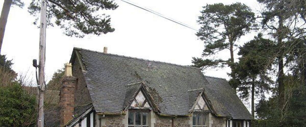 A stone cottage with a tiled roof and white-framed windows.
