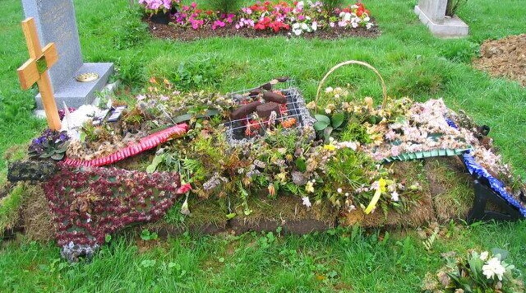 A floral tribute with a centrepiece of sausages, beefburger and kebab marking a recent grave in the churchyard at Thorpe-le-Soken.