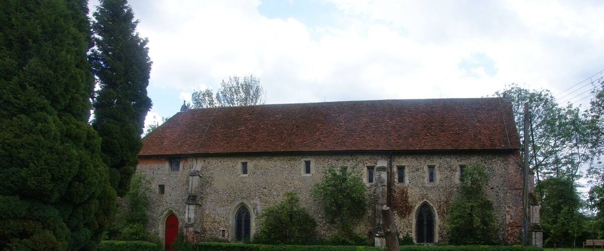 A historic building with a red-tiled roof, arched windows, and a red door.