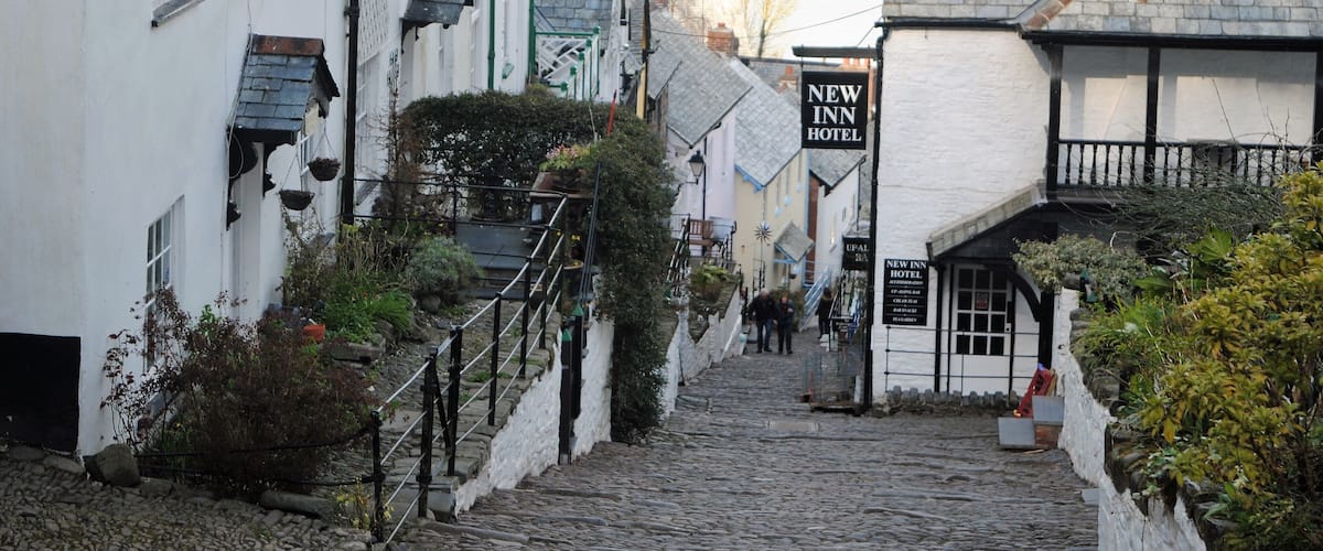 A cobblestone street lined with white buildings, including a New Inn Hotel.