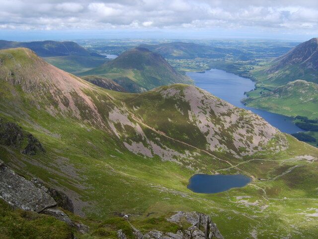 A mountainous landscape with a lake and a winding road.