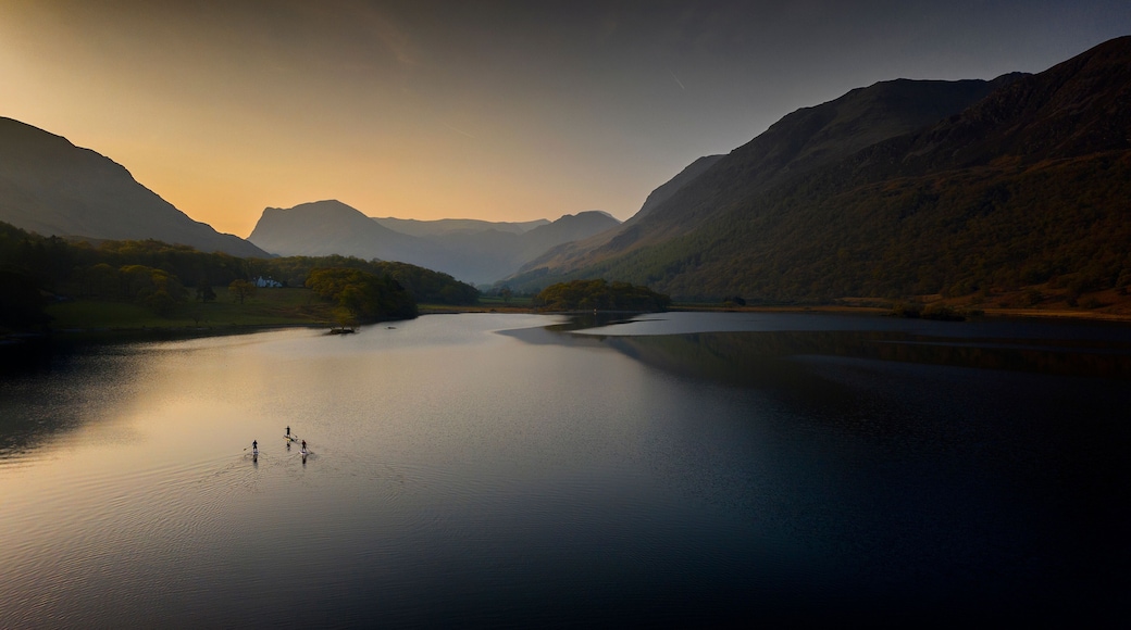 Early morning paddle boarders sail across Crummock Water a lake in the Lake District part of the UNESCO World Heritgae Centre in Cumbria.