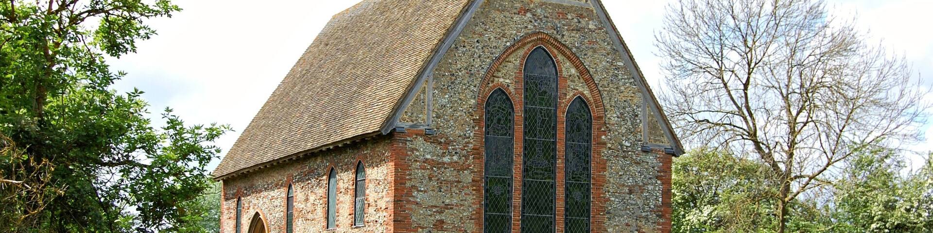 A small stone church with a steeply pitched roof and arched windows.