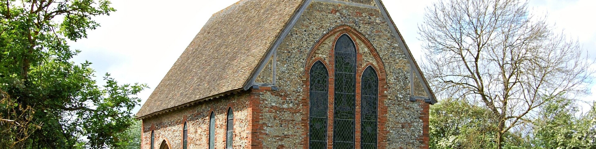 Una pequeña iglesia de piedra con techo empinado y ventanas de arco.