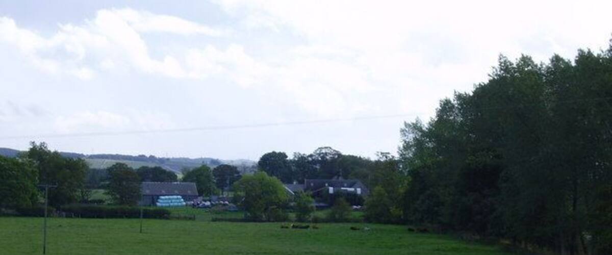 A green field with trees and a building in the distance.
