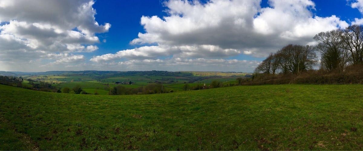 A green field with rolling hills and a partly cloudy sky.