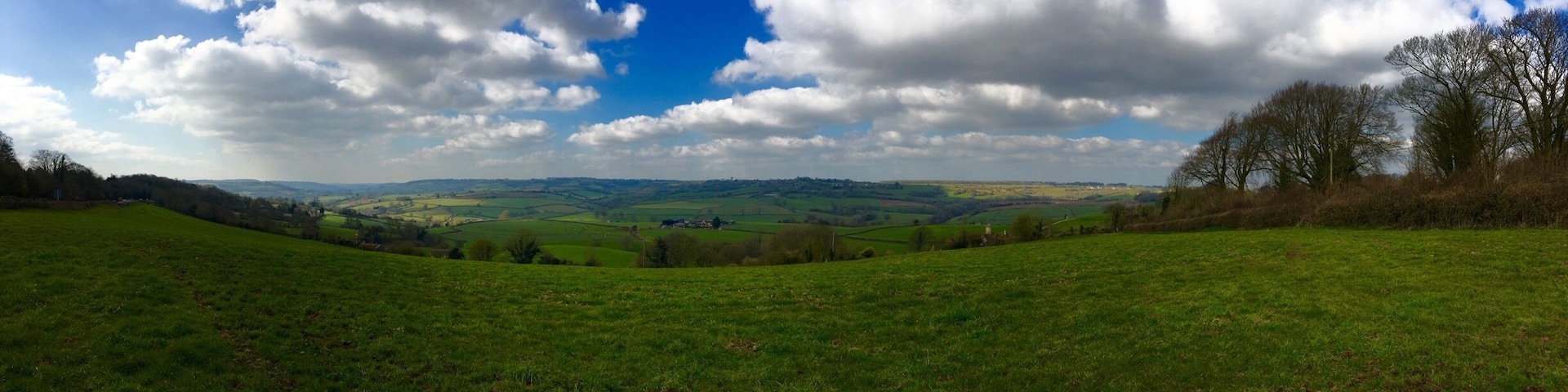 A green field with rolling hills and a partly cloudy sky.