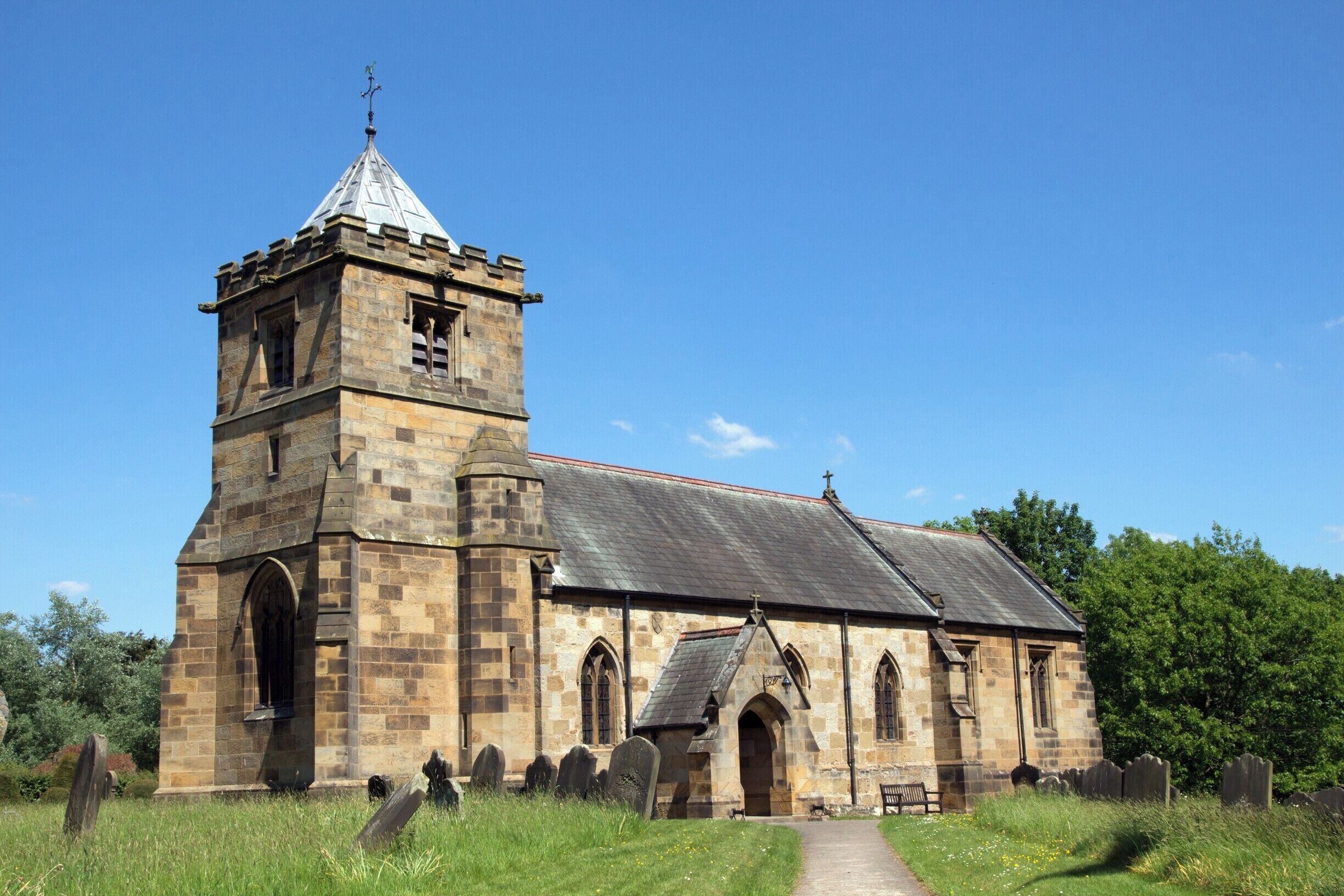 A stone church with a bell tower and a graveyard.