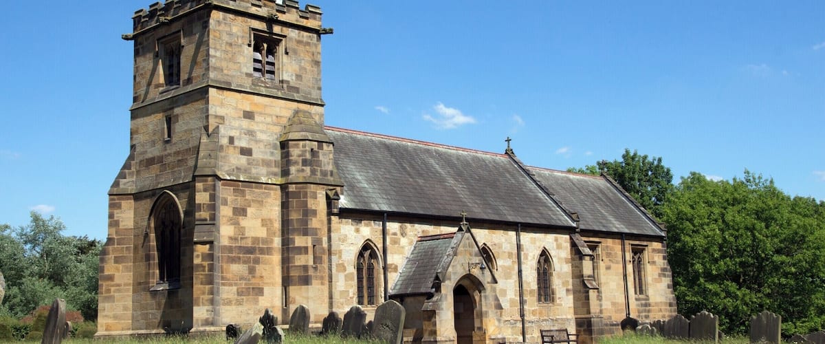 A stone church with a bell tower and a graveyard.