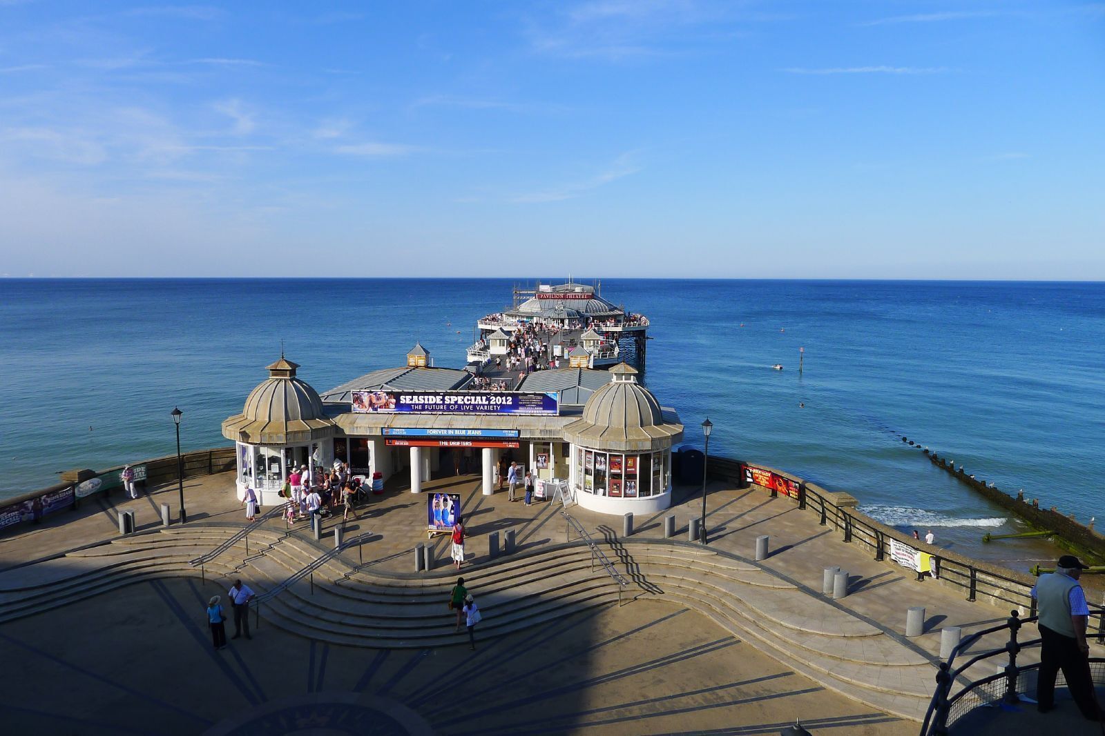 A seaside promenade with a theater, a kiosk, and a sea wall.