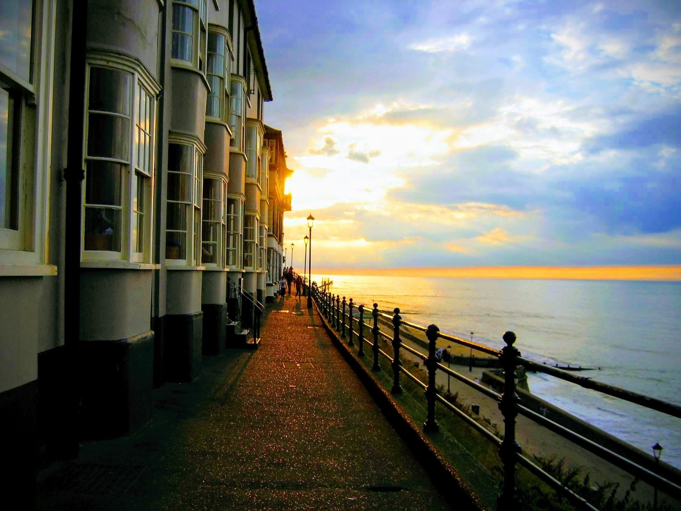 A seaside promenade with buildings on one side and the ocean on the other.
