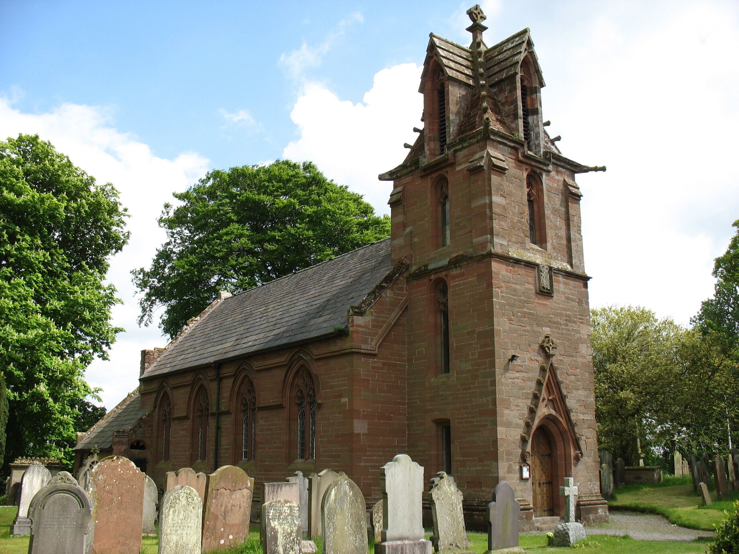 A historic church with a tall bell tower, surrounded by a cemetery.