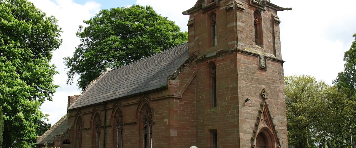 A historic church with a tall bell tower, surrounded by a cemetery.