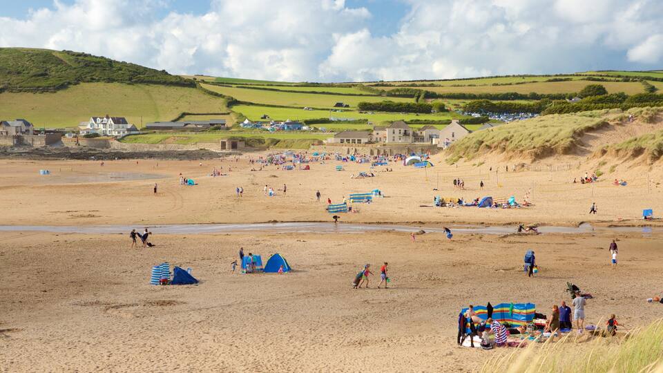 A beach with tents, people, and a hilly landscape in the background.