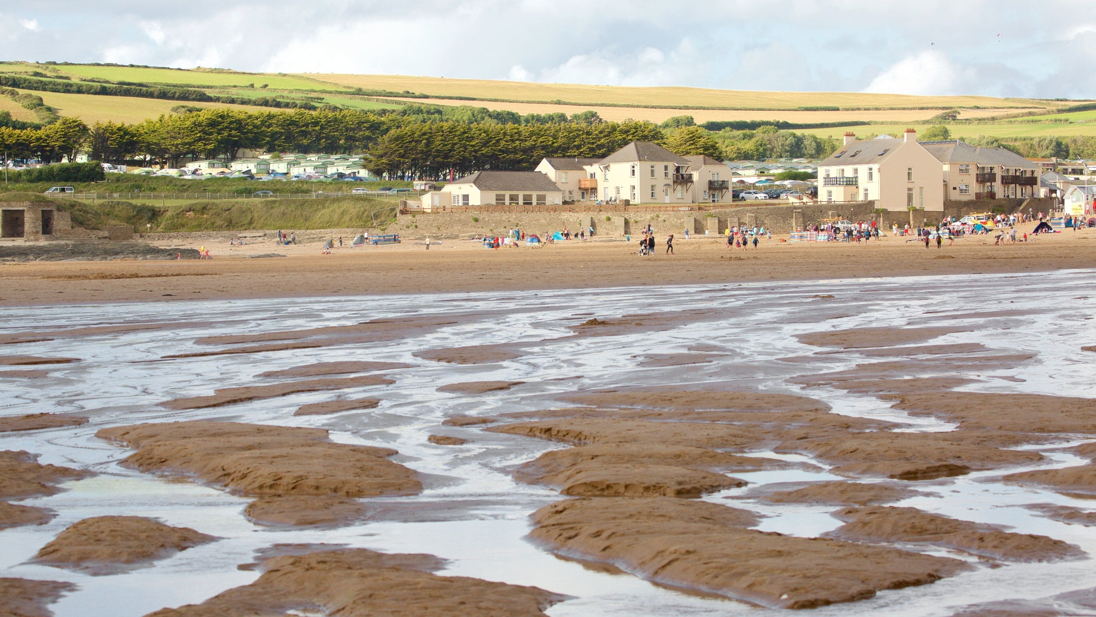Croyde which includes a coastal town and a beach as well as a large group of people