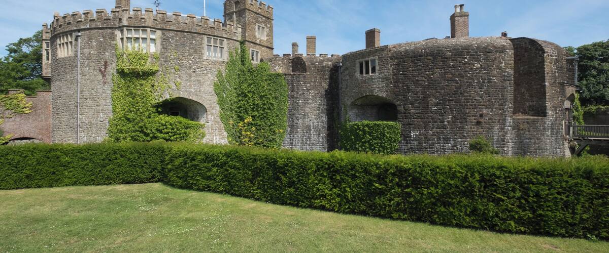 A historic castle with stone walls, arched windows, and a flagpole.