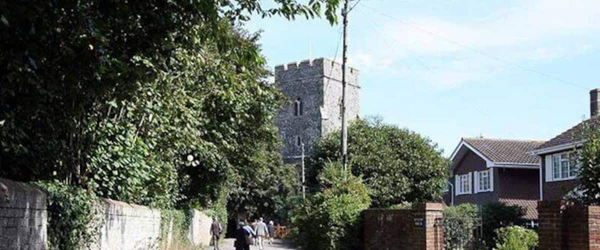 A narrow road flanked by houses and a stone tower in the distance.