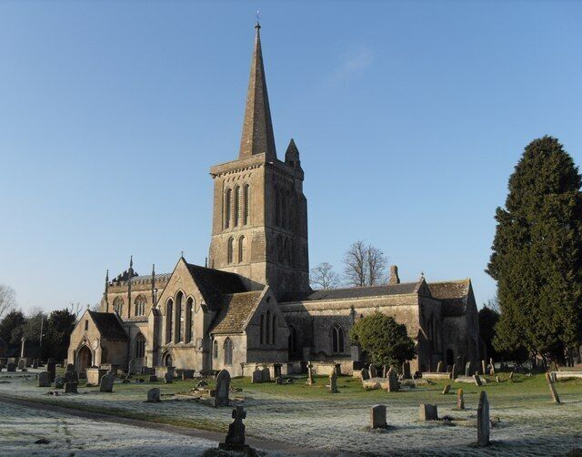A church with a tall spire and a graveyard in front.