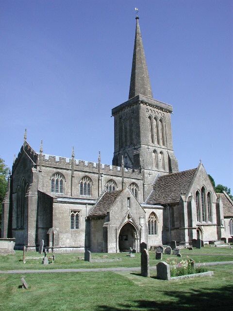 A church with a tall spire and a graveyard in front.