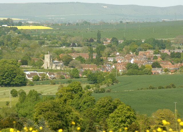 A rural village with a church, houses, and surrounding fields.