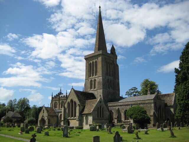 A church with a tall spire, surrounded by a cemetery with headstones.