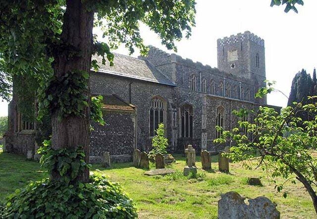 A historic church with a tall tower, surrounded by a cemetery with headstones.
