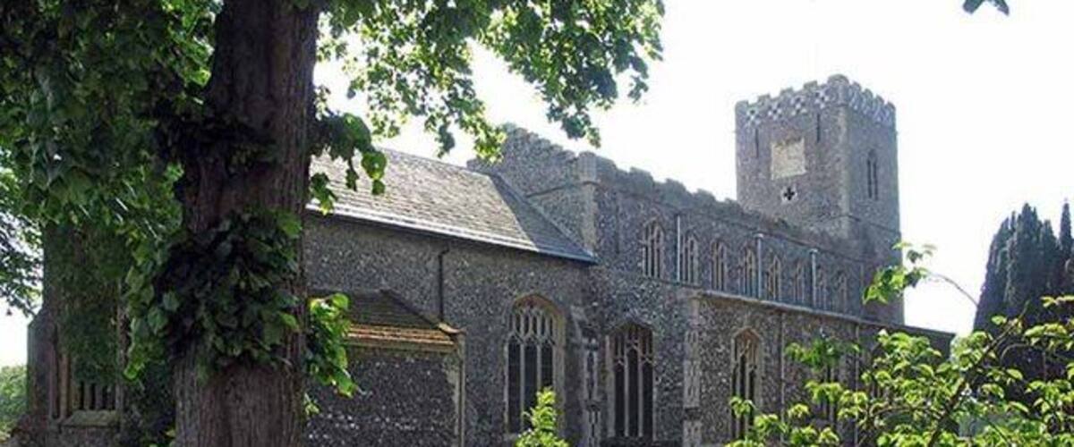 A historic church with a tall tower, surrounded by a cemetery with headstones.