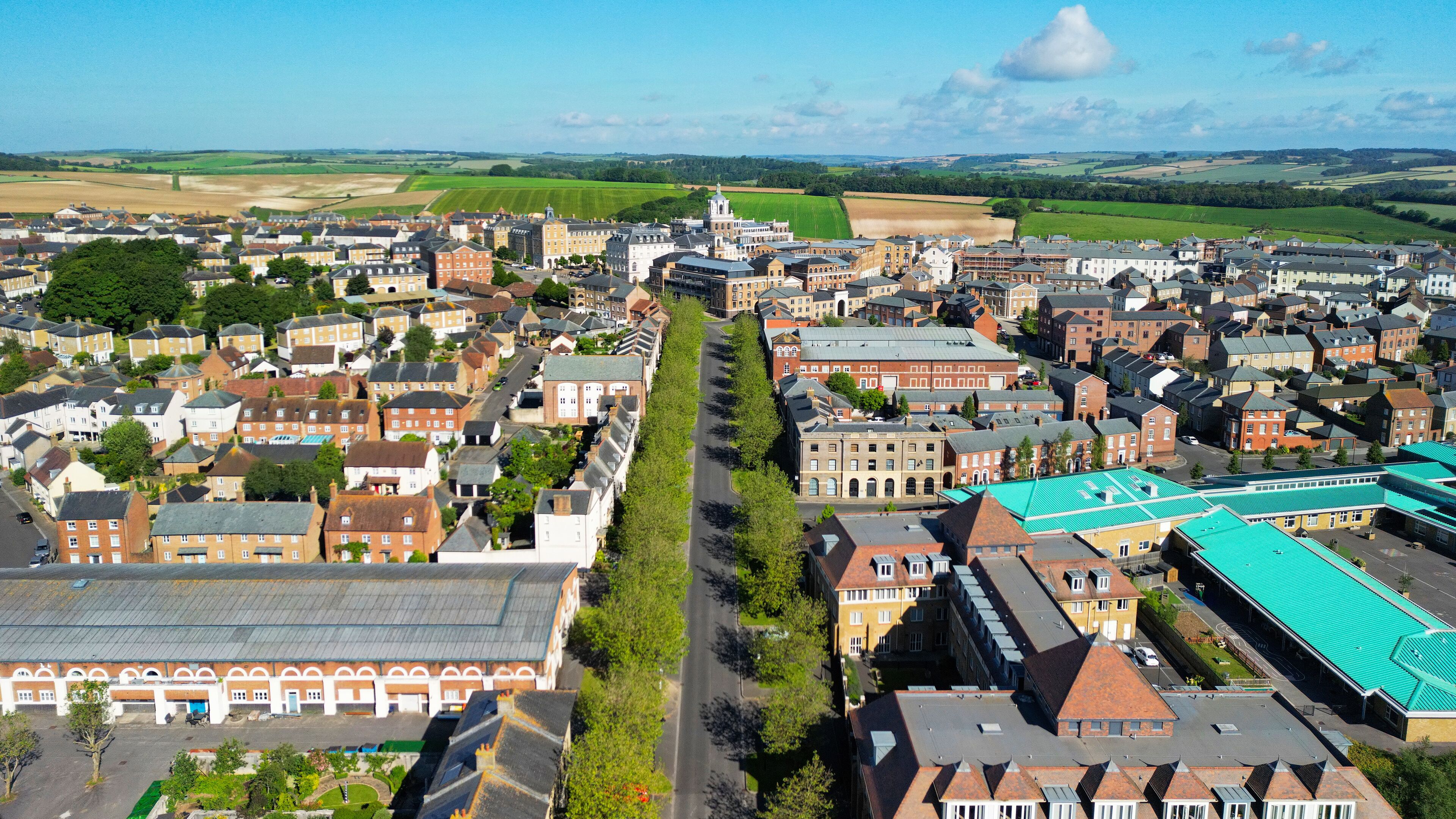 A town with a central green street, historic buildings, and surrounding fields.