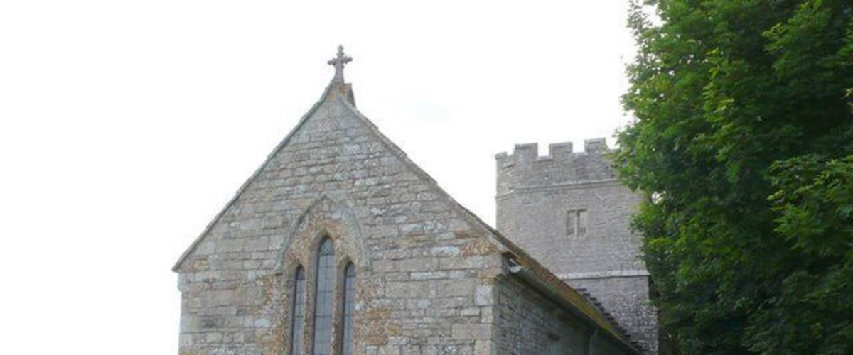 A stone church with a bell tower and a graveyard.
