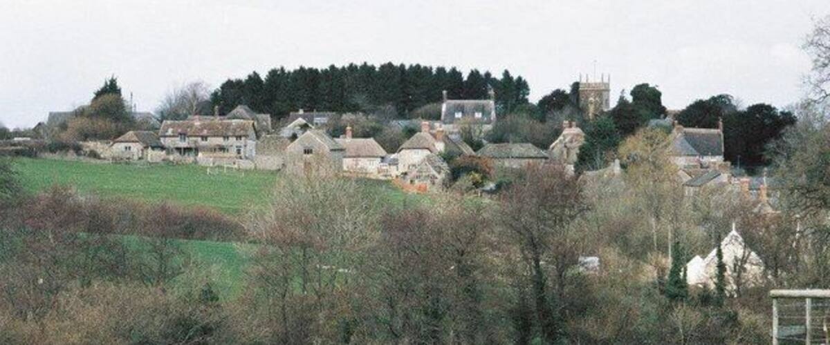 A rural village with houses, a church, and a hill in the background.