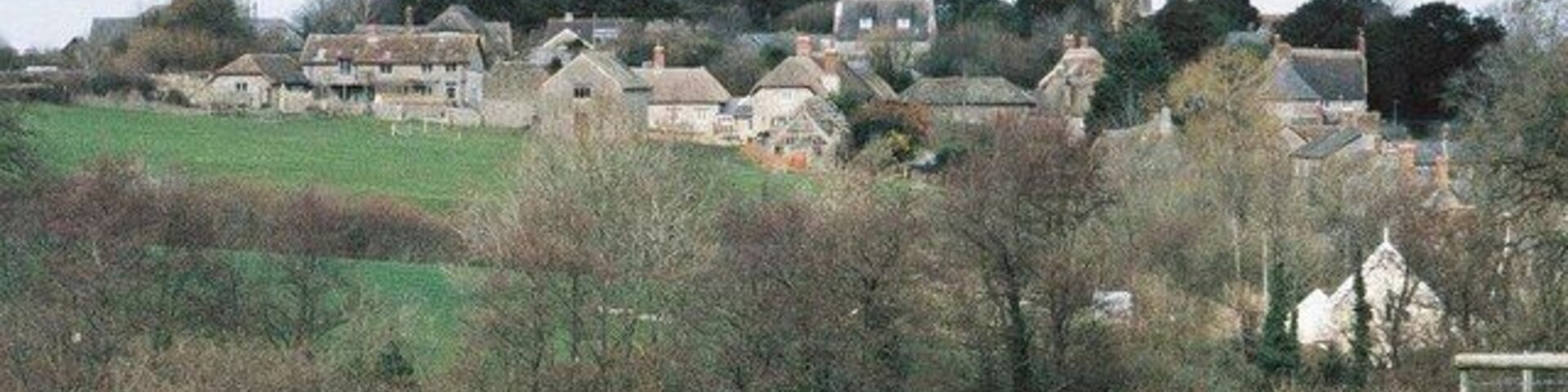 A rural village with houses, a church, and a hill in the background.