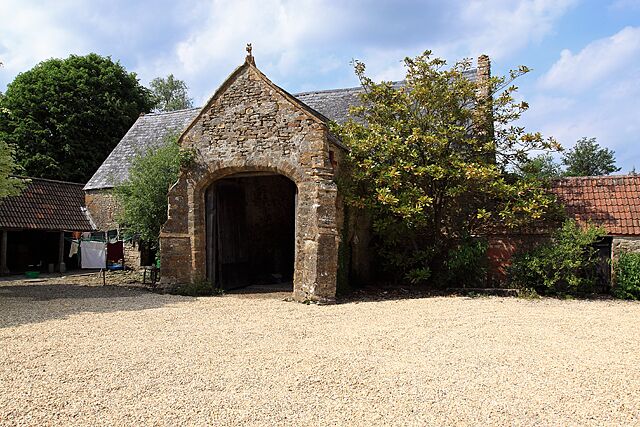 A stone building with a pointed roof and an arched entrance.