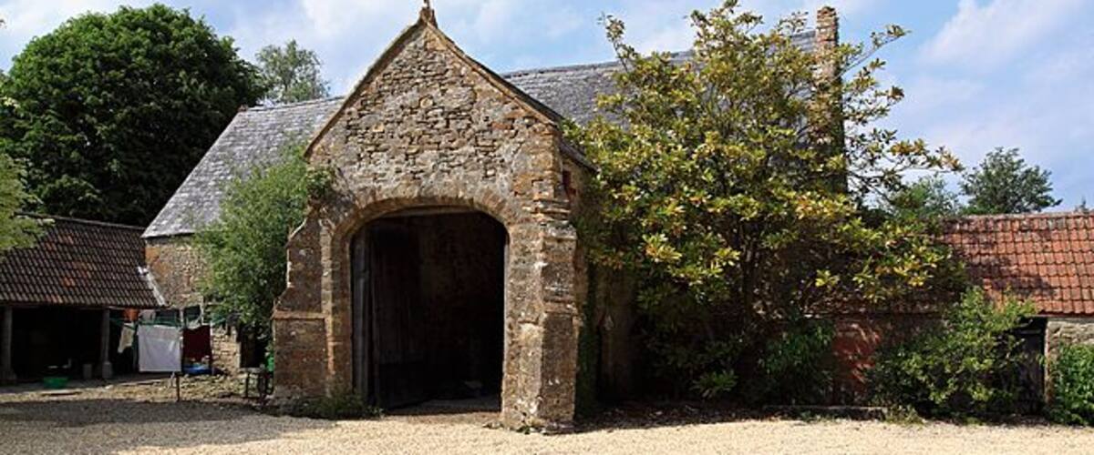 A stone building with a pointed roof and an arched entrance.
